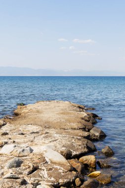 Denizin sakin, mavi sularına uzanan bir taş iskelenin sakin manzarası, yaz tatili..