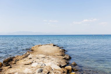 Denizin sakin, mavi sularına uzanan bir taş iskelenin sakin manzarası, yaz tatili..