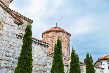 Muhteşem St. Naum Manastırı, Ohri Gölü boyunca, Bizans mimarisi, Doğu Ortodoks manastırı, geleneksel taş mimarisi ve kırmızı çatıları, kasvetli gökyüzü.