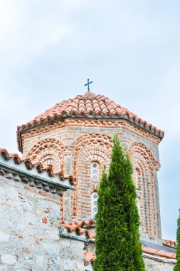 Muhteşem St. Naum Manastırı, Ohri Gölü boyunca, Bizans mimarisi, Doğu Ortodoks manastırı, geleneksel taş mimarisi ve kırmızı çatıları, kasvetli gökyüzü.