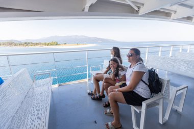 Feribot sıralarında oturan aile, Yunanistan 'daki deniz ve dağların nefes kesici manzarasının keyfini çıkarıyor.