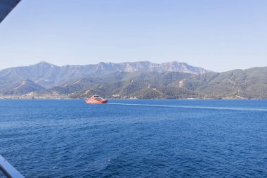 Feribot Yunanistan 'ın berrak mavi sularında yol alırken, arka planda dağlar vardı. Yaz tatili.