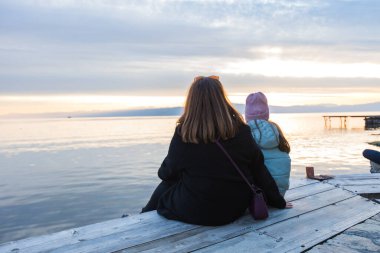 Bir ailenin günbatımında sakin göl manzarasının tadını çıkardığı sakin bir an..
