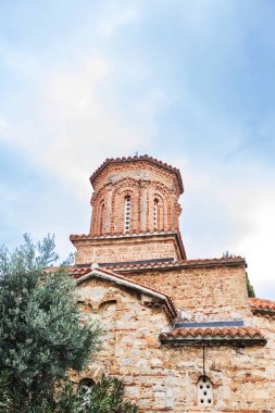 Muhteşem St. Naum Manastırı, Ohri Gölü boyunca, Bizans mimarisi, Doğu Ortodoks manastırı, geleneksel taş mimarisi ve kırmızı çatıları, kasvetli gökyüzü.