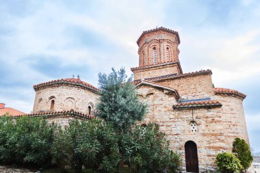 Muhteşem St. Naum Manastırı, Ohri Gölü boyunca, Bizans mimarisi, Doğu Ortodoks manastırı, geleneksel taş mimarisi ve kırmızı çatıları, kasvetli gökyüzü.