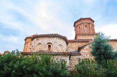 Muhteşem St. Naum Manastırı, Ohri Gölü boyunca, Bizans mimarisi, Doğu Ortodoks manastırı, geleneksel taş mimarisi ve kırmızı çatıları, kasvetli gökyüzü.