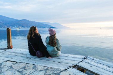 Yetişkin ve Çocuk Birlikte Oturuyor Ahşap İskelede Günbatımında Huzurlu Waterscape 'in tadını çıkarıyorlar