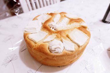  Madalyalı yuvarlak bir somun, muhtemelen bir Slavski Kola desenli bir yüzey üzerinde sunuluyor, hamur bazlı süslemeler içeriyor, kültürel ya da kutlama bağlamında.