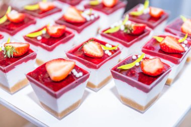 Zarif çilek bardakları krema, bisküvi ve ahududu soslu.