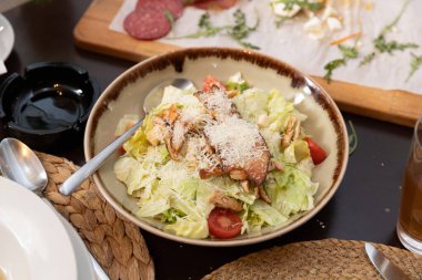 İçinde kıtır marul, ızgara tavuk, kıtır ekmek, vişneli domates ve bol rendelenmiş parmesan peyniri olan taze Sezar salatası servis ediliyor. Klasik bir restoran favorisi..