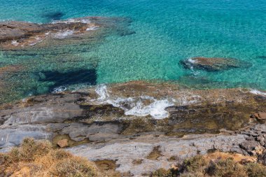 Yüksek açılı manzara, şaşırtıcı derecede berrak turkuaz suyu kayalık bir kıyı şeridiyle buluşurken gösteriyor. Engebeli, bozulmamış kıyı manzarasında denizin doğal güzelliğini ve şeffaflığını ön plana çıkarıyor..