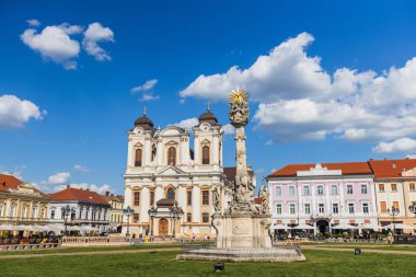 Geniş açı, tarihi binalar ve canlı açık kafelerle çevrili Timisoara 'nın canlı Union Meydanı' na (Piata Unirii) hakim olan St. George Katedrali 'nin ikonik beyaz cephesini yakalar..