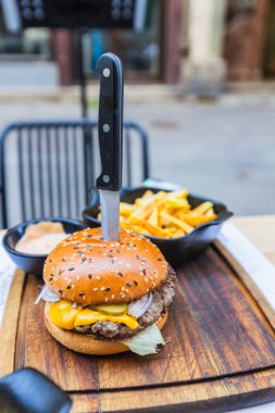 Gurme Cheeseburger ve Altın Patates Kızartması Restoran 'da Tahta Tahta Tahta Masa' da Sosu ve Bıçak Sunumuyla servis ediliyor