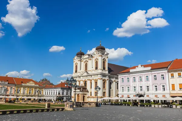 Geniş açı, tarihi binalar ve canlı açık kafelerle çevrili Timisoara 'nın canlı Union Meydanı' na (Piata Unirii) hakim olan St. George Katedrali 'nin ikonik beyaz cephesini yakalar..