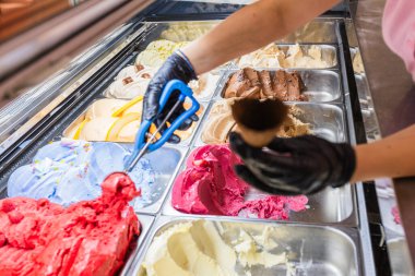 Gelato Dükkanı Sunucusu Profesyonel Mavi Kepçe Aracı ile Renkli İtalyan Dondurması Kakalıyor