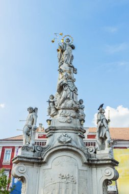 Romanya 'nın Timisoara kentindeki tarihi Özgürlük Meydanı' nda belirgin bir şekilde duran, birden fazla figür ve heykelle süslenmiş uzun ve süslü taş bir heykelin ayrıntılı manzarası.