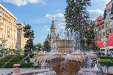 Romanya 'nın muhteşem Ortodoks Katedrali' ne doğru bir manzara sunan Timisoara 'nın hareketli Zafer Meydanı' nın (Piata Victoriei) ön planında ferahlatıcı çeşmeler akıyor.