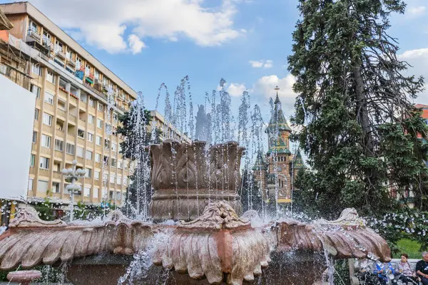 Romanya 'nın muhteşem Ortodoks Katedrali' ne doğru bir manzara sunan Timisoara 'nın hareketli Zafer Meydanı' nın (Piata Victoriei) ön planında ferahlatıcı çeşmeler akıyor.