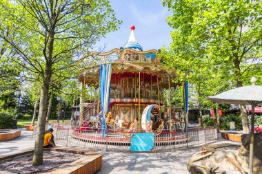 Vintage Double-Decker Carousel with Ornate Decorations and Painted Horses in Public Park Surrounded by Trees clipart