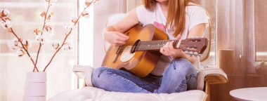 Bayan gitarist Cotton Stems Dekorasyonuyla Konforlu Oturma Odasında Akustik Gitar Çalıyor