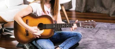 Genç Kadın Parlak Oturma Odasında Modern Sandalyede Akustik Gitar Çalıyor