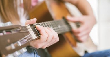 Fretboard ve Strings 'te parmak uçlarıyla Akustik Gitar Çalan Eller