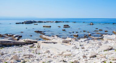 Akdeniz sahillerinde güneşli bir günde, kusursuz mavi gökyüzü altında beyaz kireçtaşı taşları ve berrak mavi deniz suyuyla güzel Rocky sahili.