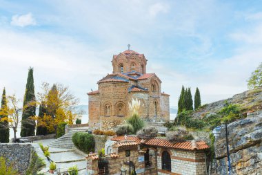 Kuzey Makedonya 'da Kaneo' daki renkli sonbahar ağaçları ve dingin sularıyla çevrili Ohri gölünün üzerinde tünemiş büyüleyici Aziz John kilisesi.