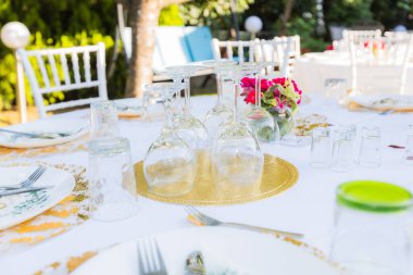 Bahçe partisi ya da düğün resepsiyonu için şarap kadehleri ve çiçeklerle süslenmiş şık bir masa.