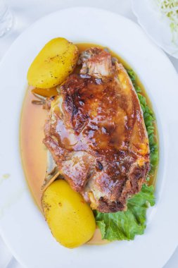 Lezzetli kavrulmuş kuzu eti ve soslu altın patates. Beyaz tabakta servis ediliyor. Geleneksel Akdeniz mutfağı ve konforlu yemekler sergileniyor..
