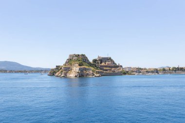 Korfu 'nun tarihi Eski Kalesi, berrak bir yaz gökyüzünün altında sakin, derin mavi İyon Denizi ile çevrili kayalık bir yarımadada görkemli bir şekilde duruyor..