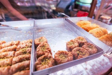 Şam fıstığıyla süslenmiş, bal şurubuna batırılmış ve otantik tatlı pazarında servis edilen metal tepsilerde sergilenen geleneksel geleneksel Orta Doğu hamur işleri kültür mirasını gözler önüne seriyor..
