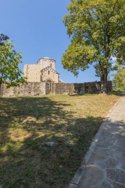 Sırbistan 'ın tarihi Ras bölgesi olan yemyeşil ağaçlarla çevrili, kendine özgü yuvarlak kulesi ve taş sağlamlaştırma duvarlarıyla Aziz George Manastırı' nın Romen Ortaçağ mimarisi yolları.