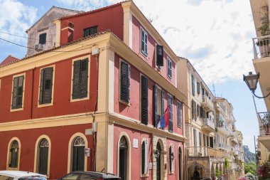 Yunanistan 'ın eski Corfu kentinin dar sokaklarındaki bir pencereden süzülen Sırp bayrağına sahip tarihi, terracotta renkli bir bina, eşsiz bir kültürel bağlantı sergiliyor.