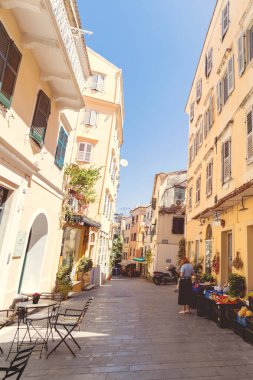 Tarihi Corfu eski kasabasında kaldırım taşı kaldırımları boyunca işlenmiş demir bistro masaları ve çizgili sandalyeleri olan açık hava kafe terasını davet ediyorum..