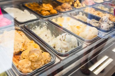 Cam tabakanın arkasındaki metal tepsilerde sergilenen çeşitli parlak renkli dondurmaların yakın çekim ve iştah açıcı görüntüsü kremalı ve dondurulmuş tatlılar servis edilmeye hazır..