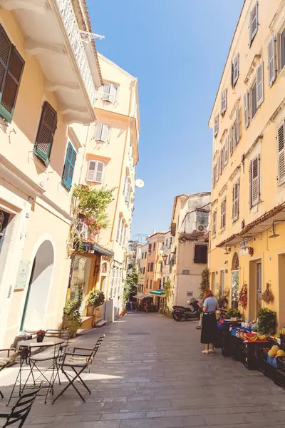 Tarihi Corfu eski kasabasında kaldırım taşı kaldırımları boyunca işlenmiş demir bistro masaları ve çizgili sandalyeleri olan açık hava kafe terasını davet ediyorum..