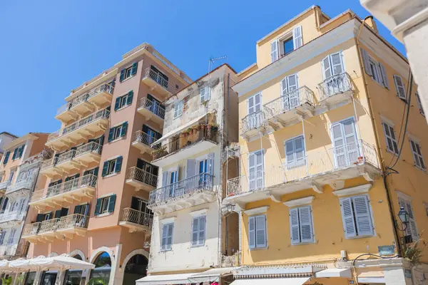 Corfu Eski Kasabası 'ndaki birkaç tarihi binanın detaylı görüntüsü, çeşitli katları, klasik balkonları ve açık mavi gökyüzü altında çeşitli renkli panjurları olan geleneksel mimariyi gözler önüne seriyor..