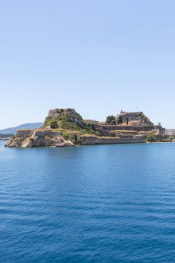 Korfu Kasabası 'nın renkli kıyı şeridinin geniş ve manzaralı bir manzarası. Parlak, güneşli bir günde engin mavi İyon Denizi' nden görünen tarihi binalar ve Eski Kale 'yi gösteriyor..