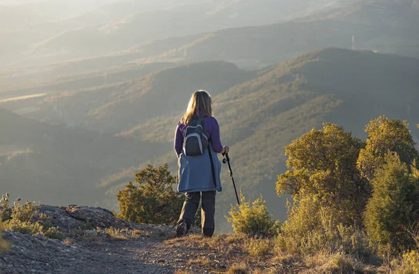 一位妇女一边悠闲自在地徒步旅行 一边提着背包和身边的环境 怀着对高山美景的敬畏之情站在那里 — 图库照片