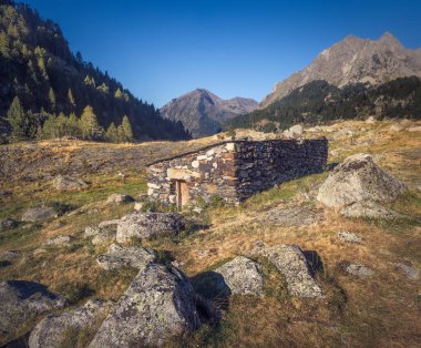 Serene stones nestled among boulders, framed by majestic mountains in the Spanish Pyrenees. clipart