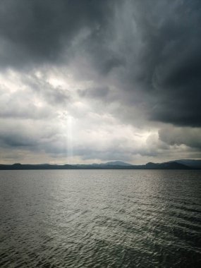 Üzerinde bulutlu bir gökyüzü olan göl. Gökyüzü karanlık ve su sakin.