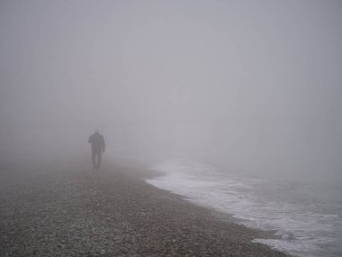 Sisli sahilde yürüyen bir adam