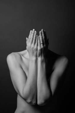 İki eliyle yüzünü örten, incinebilirliğini, utancını ve duygusal mücadelesini ifade eden çıplak bir kadının siyah ve beyaz sanatsal görüntüsü.