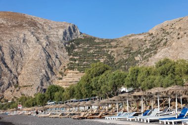 Kamari, Santorini, Yunanistan - 3 Temmuz 2021: Santorini 'deki siyah volkanik Kamari plajında güneşlik. Cyclades, Yunanistan