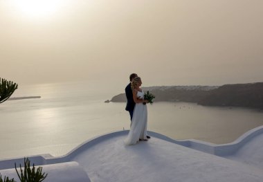 Imerovigli, Santorini, Yunanistan - 1 Temmuz 2021: Santorini Adası 'nda Imergovigli' de romantik bir fotoğraf çekimi sırasında gelin ve damat.