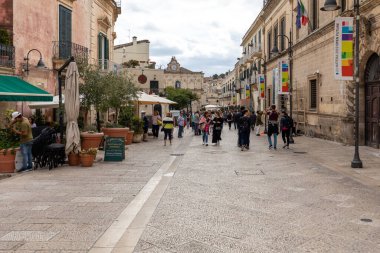 Matera, İtalya - 20 Eylül 2019: Matera şehrinin tarihi bir bölgesi olan Sassi di Matera 'daki Cobblestone caddesinde yürüyüş yapan turistler. Basilicata. İtalya