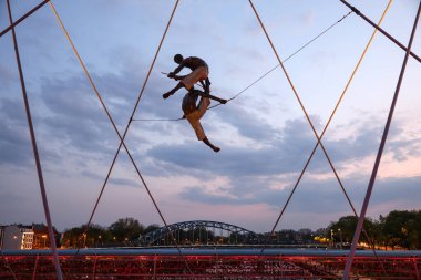 Cracow, Polonya - 2 Mayıs 2022: Krakow 'daki Vistula Nehri üzerindeki Kornatka yaya köprüsünde Jerzy Kedziora tarafından gökyüzü ile su arasında dengeli heykeller