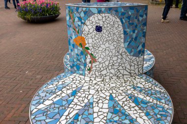 Lahey, Hollanda - 17 Nisan 2023: Uluslararası Adalet Divanı 'nın yer aldığı Lahey' deki Barış Sarayı önünde barış simgesi olarak elinde zeytin dalı tutan beyaz bir güvercin kürsüsü