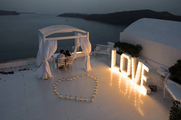 Imerovigli サントリーニ島 ギリシャ 2021年7月1日 ロマンチックな夜には テラスからサントリーニ島の夕日を賞賛するカップル — ストック写真